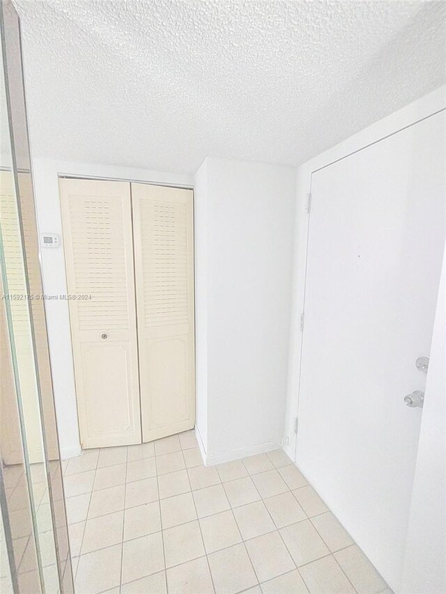 unfurnished bedroom featuring light tile patterned flooring, a closet, and a textured ceiling