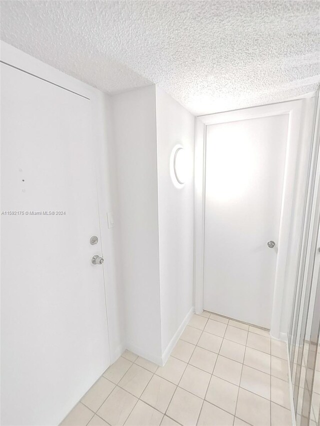 empty room with light tile patterned flooring and a textured ceiling