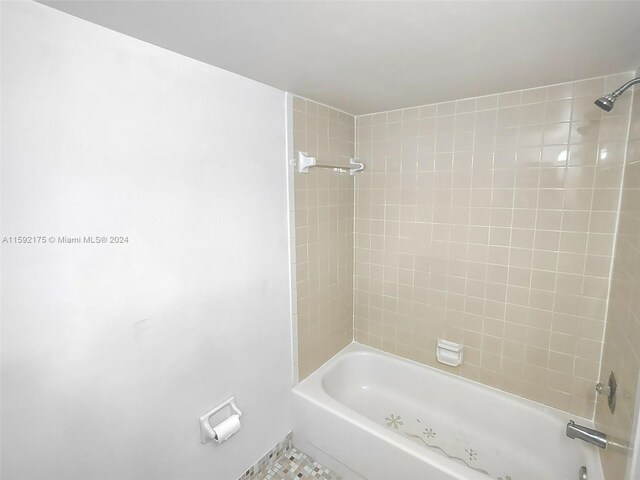 bathroom featuring tiled shower / bath combo, toilet, and tile patterned floors