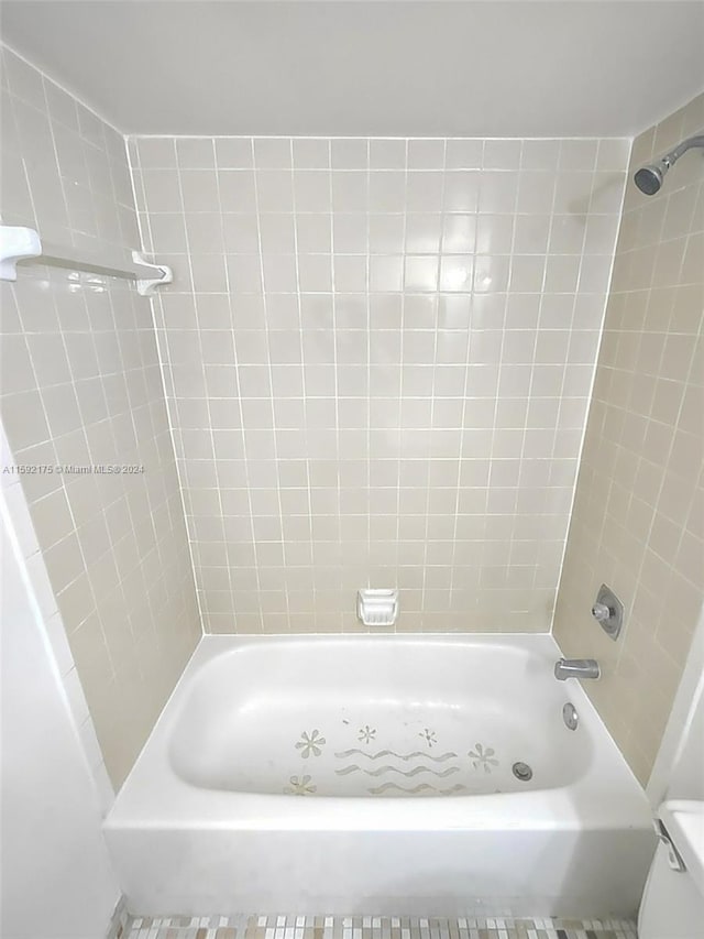 bathroom featuring toilet and tiled shower / bath