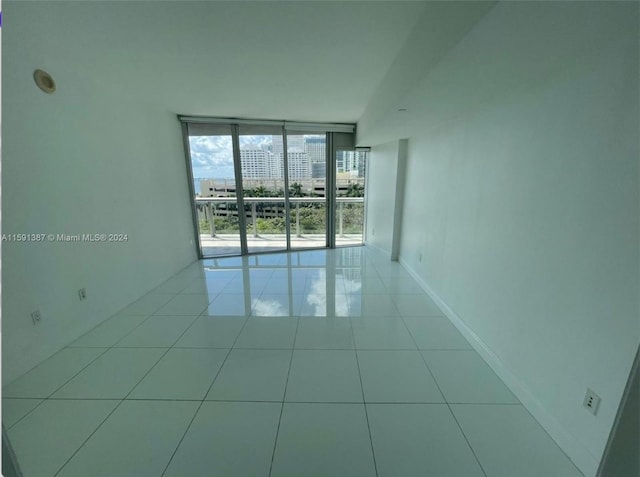 spare room with light tile patterned flooring and a wall of windows