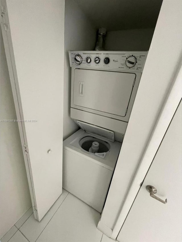 laundry room with light tile patterned flooring and stacked washer and clothes dryer