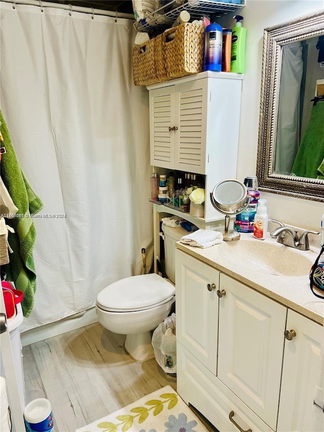 bathroom with hardwood / wood-style flooring, toilet, and vanity