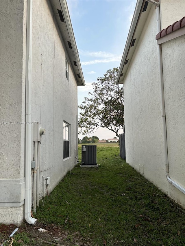 view of side of home with central AC and a lawn