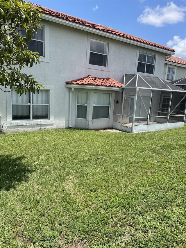 back of house with a sunroom and a lawn