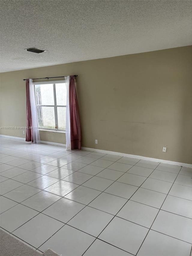 unfurnished room featuring light tile flooring and a textured ceiling