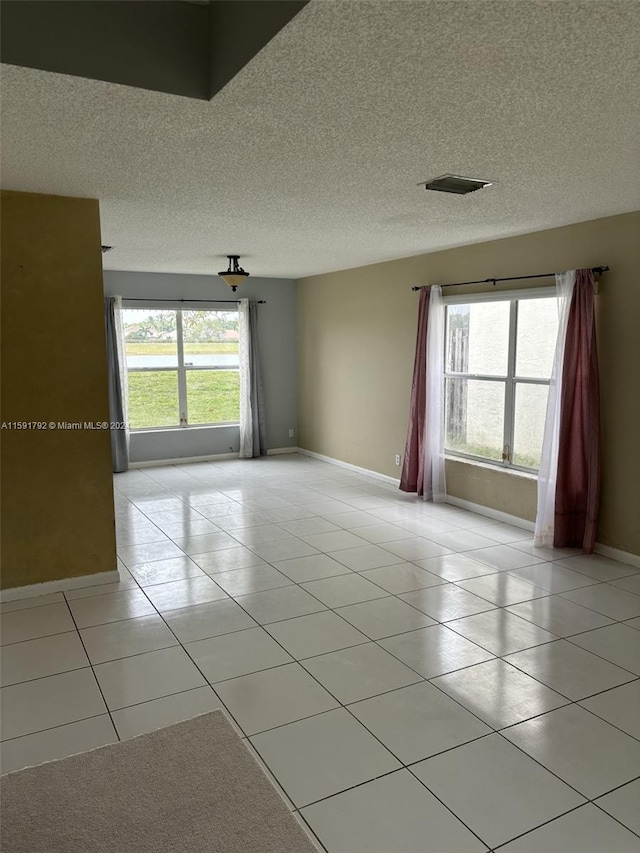 unfurnished room with a textured ceiling and light tile floors