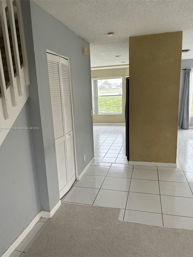 hall with light carpet and a textured ceiling