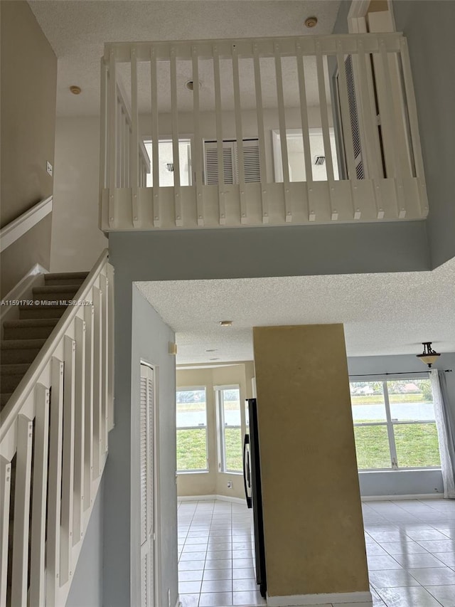 stairs featuring light tile flooring and a textured ceiling