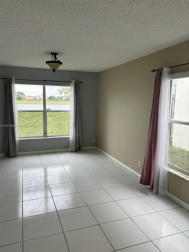 unfurnished room with a healthy amount of sunlight, light tile flooring, and a textured ceiling