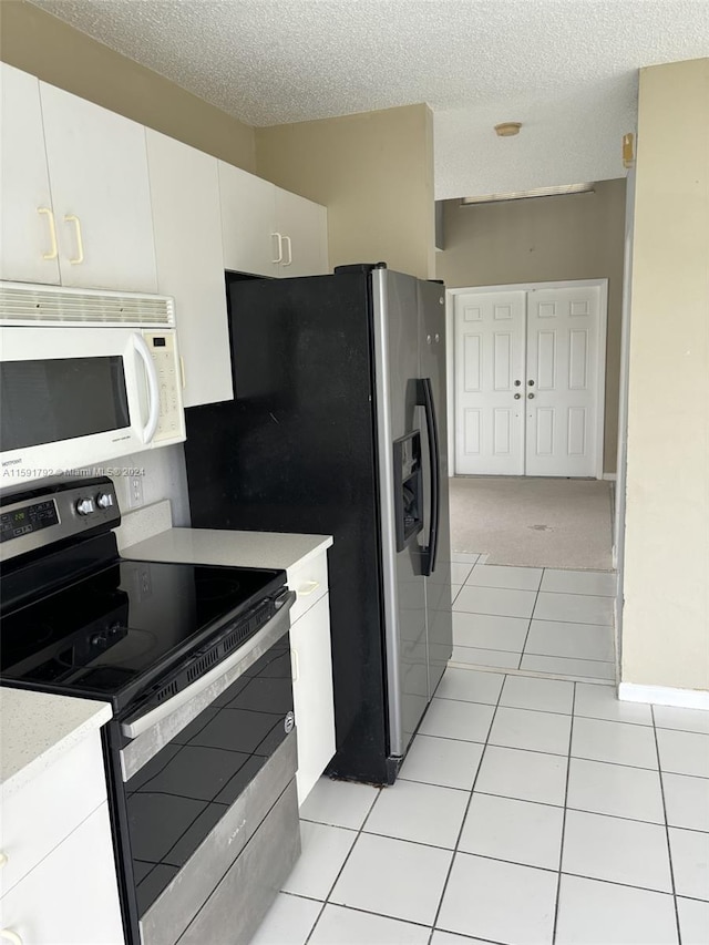 kitchen featuring electric stove, white cabinets, light tile floors, and a textured ceiling