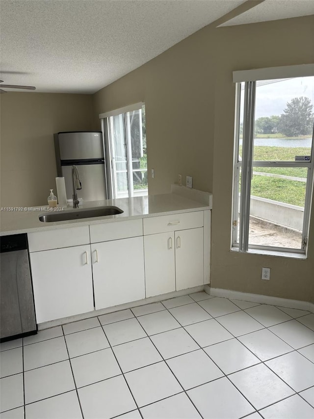 kitchen with stainless steel appliances, light tile floors, white cabinetry, sink, and a textured ceiling