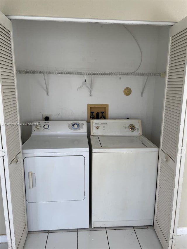 laundry area with hookup for a washing machine, washer and clothes dryer, electric dryer hookup, and light tile floors