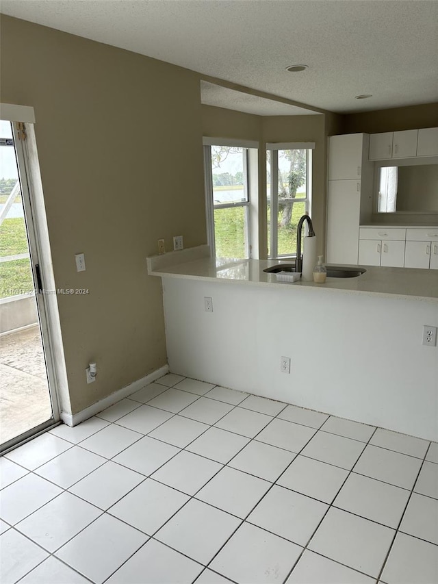 tiled empty room featuring sink, a textured ceiling, and a wealth of natural light