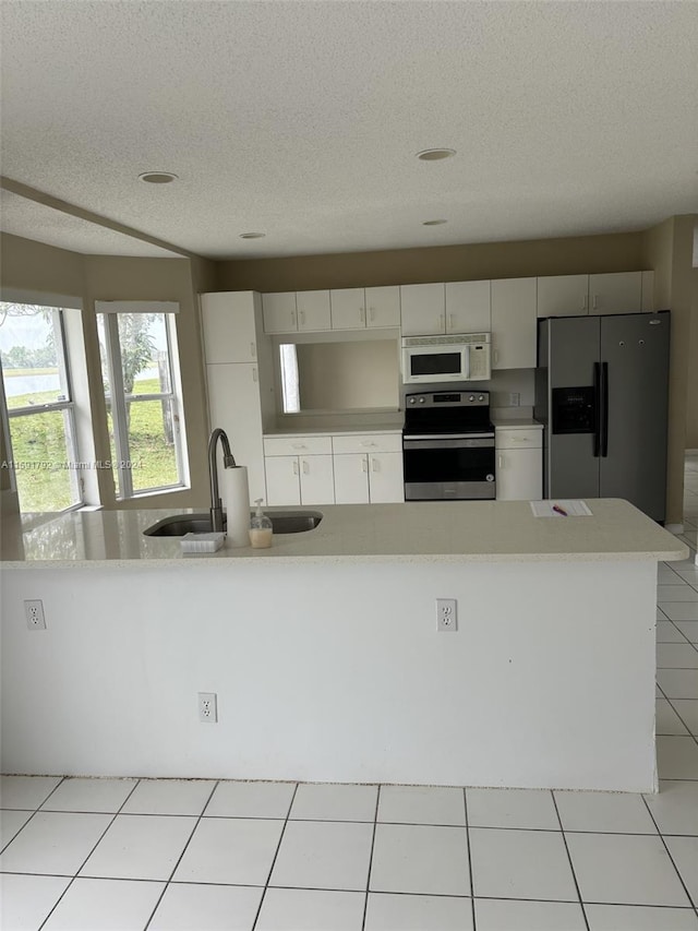 kitchen with stainless steel appliances, a textured ceiling, light tile floors, sink, and white cabinets