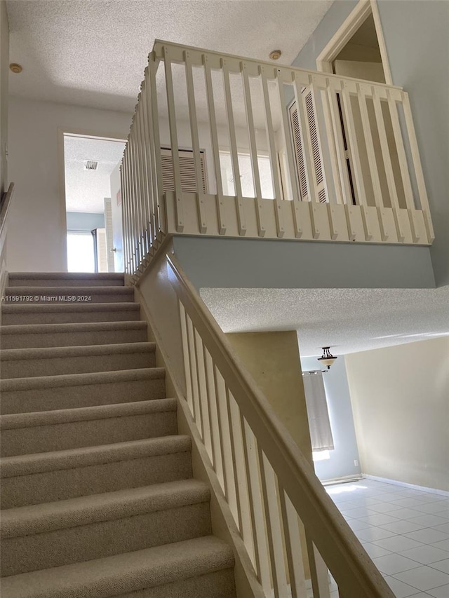 stairs featuring tile floors and a textured ceiling