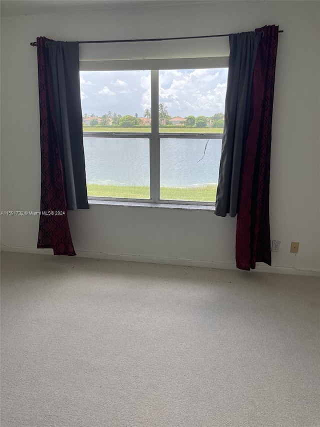 carpeted spare room with a water view