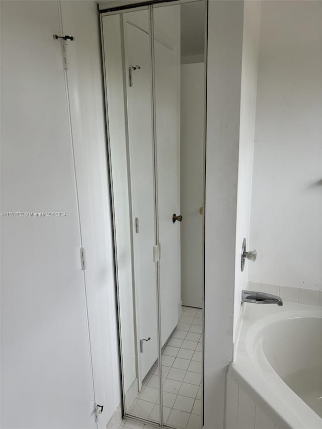 bathroom featuring tile flooring and tiled tub