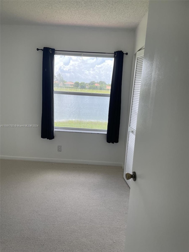 carpeted spare room with a textured ceiling and a water view