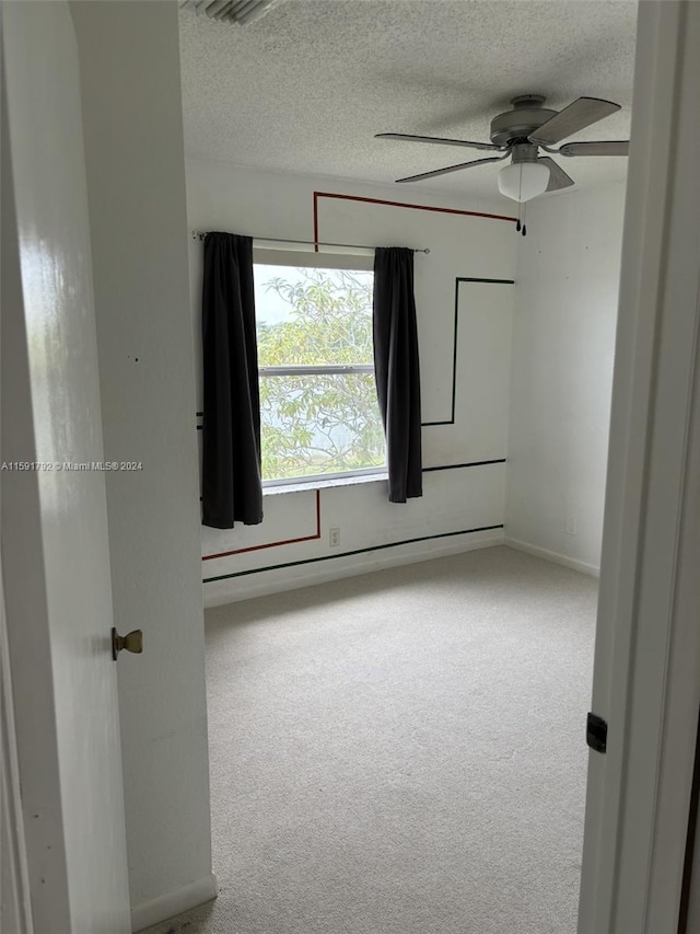 empty room featuring carpet flooring, ceiling fan, and a textured ceiling