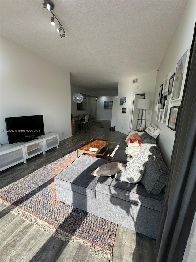 living room with a textured ceiling, hardwood / wood-style flooring, a chandelier, and rail lighting