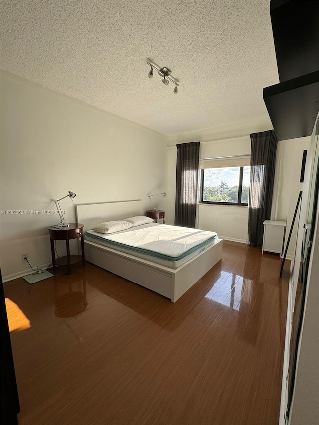 unfurnished bedroom with a textured ceiling and dark hardwood / wood-style flooring