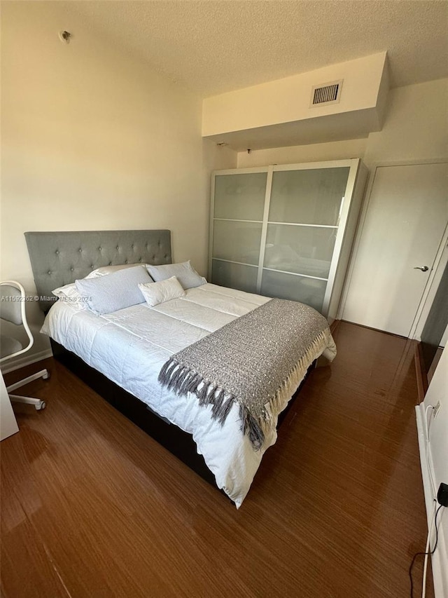 bedroom with a textured ceiling and dark hardwood / wood-style floors