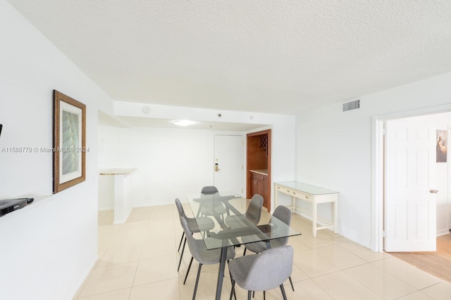 dining area featuring a textured ceiling and light tile floors