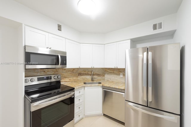 kitchen featuring light stone countertops, stainless steel appliances, light tile flooring, sink, and white cabinetry