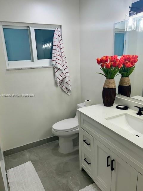 bathroom with vanity with extensive cabinet space, toilet, and concrete flooring