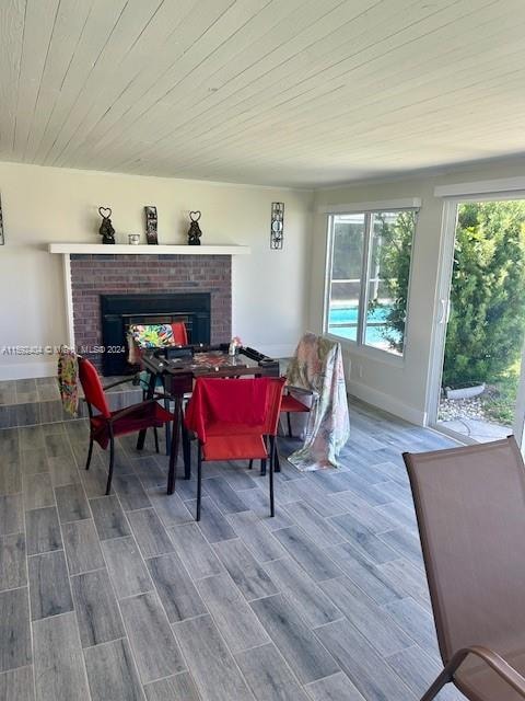 dining area with a brick fireplace, hardwood / wood-style flooring, and wooden ceiling