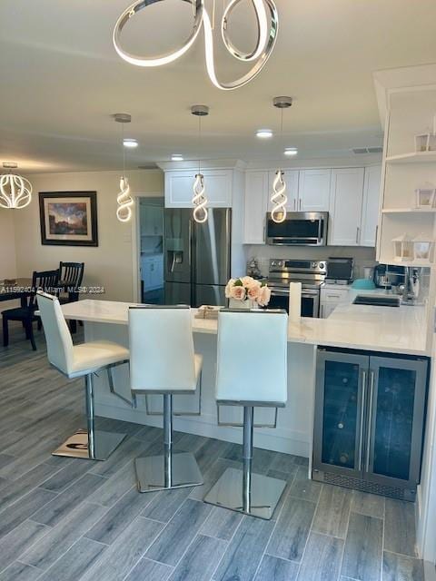 kitchen featuring stainless steel appliances, white cabinets, pendant lighting, and wood-type flooring