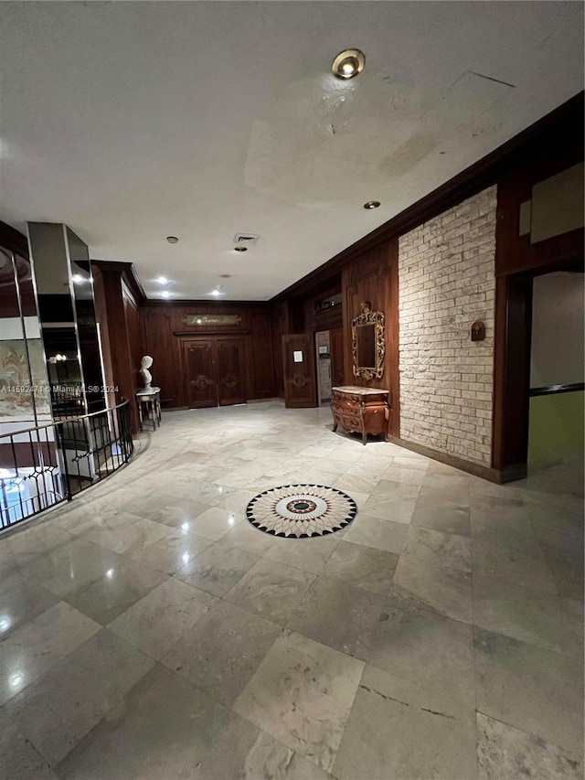 basement with wooden walls, light tile floors, and crown molding