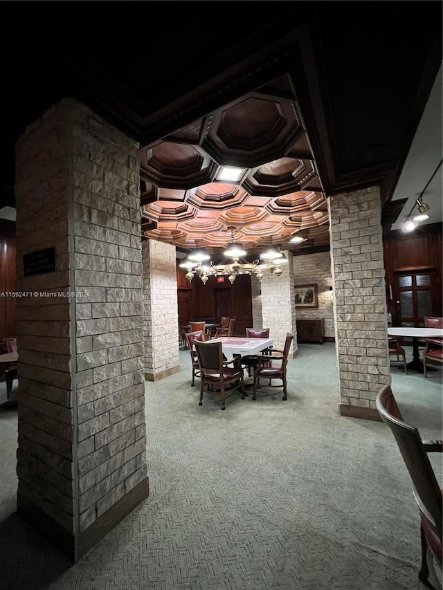 dining space with brick wall, coffered ceiling, carpet flooring, and decorative columns