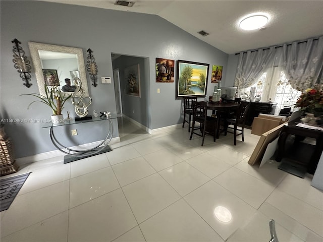 dining space with vaulted ceiling and light tile floors