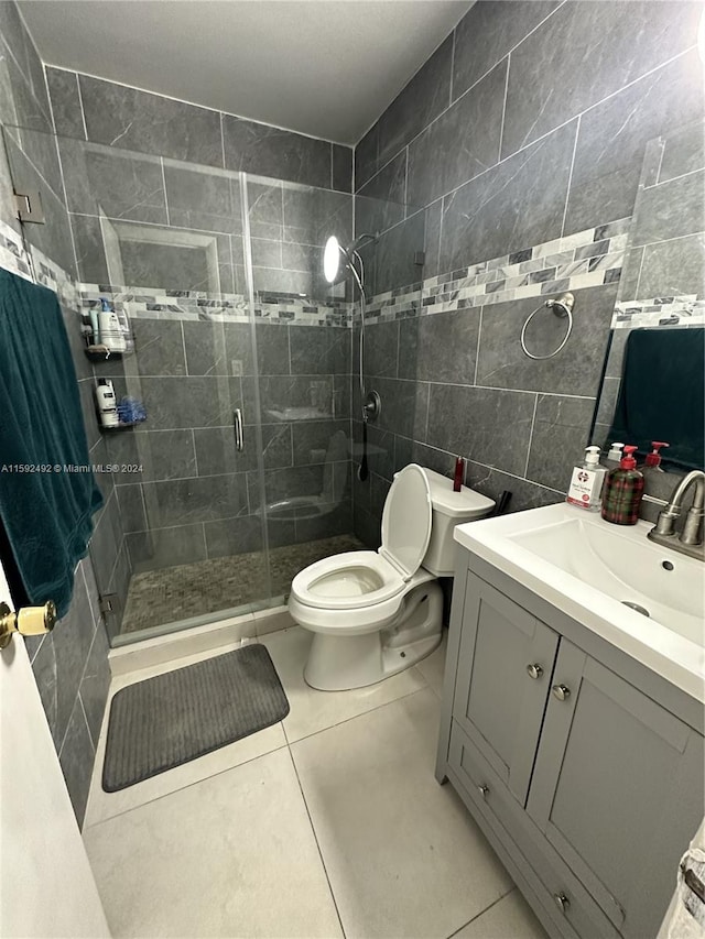 bathroom with tile flooring, an enclosed shower, vanity, and tile walls