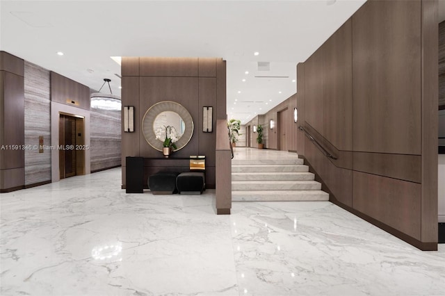 interior space with stone wall, marble finish floor, elevator, and recessed lighting