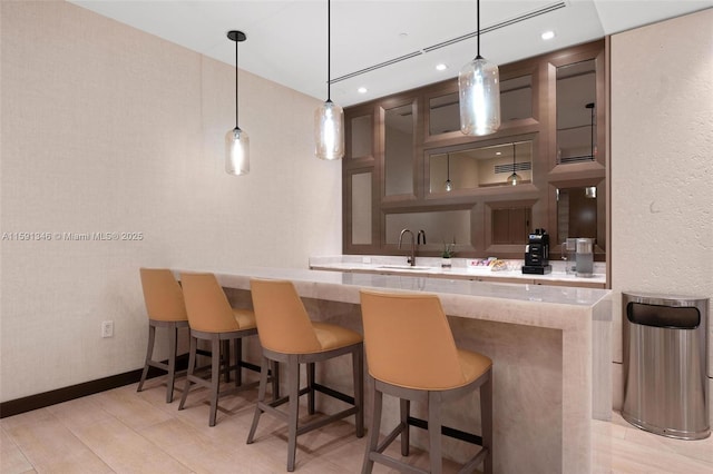 bar featuring baseboards, hanging light fixtures, a sink, and recessed lighting