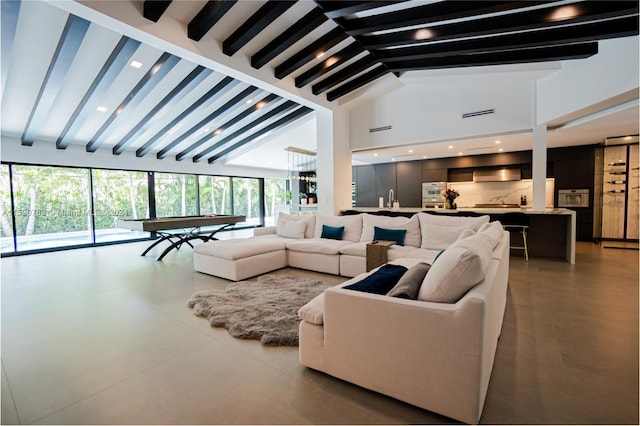 living room featuring high vaulted ceiling, sink, and beamed ceiling