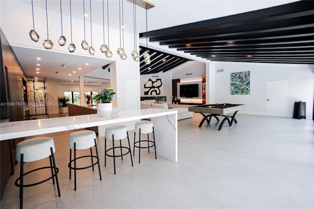 interior space with hanging light fixtures, billiards, a breakfast bar, and light tile floors