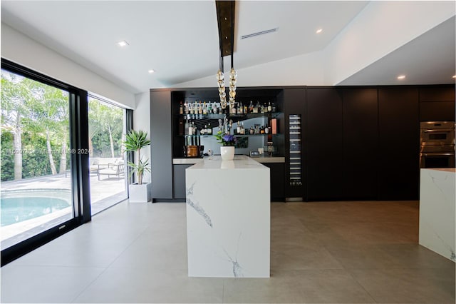 kitchen featuring light stone countertops, lofted ceiling with beams, light tile flooring, and double oven