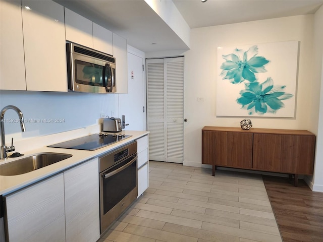 kitchen featuring stainless steel appliances, white cabinets, and sink