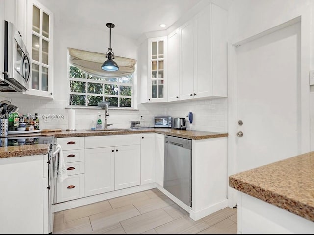 kitchen featuring decorative backsplash, white cabinetry, appliances with stainless steel finishes, decorative light fixtures, and sink