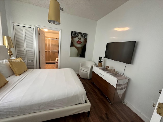 bedroom with ensuite bath, a closet, dark wood-type flooring, and a textured ceiling