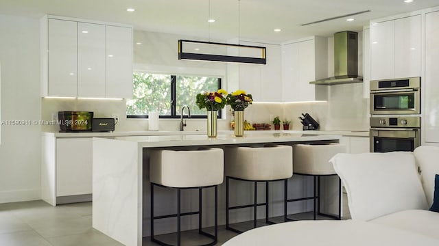 kitchen with white cabinetry, wall chimney range hood, and tasteful backsplash