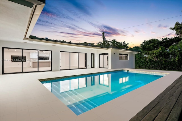 pool at dusk featuring a patio