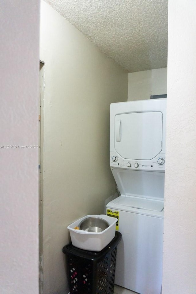 washroom with a textured ceiling and stacked washer and dryer