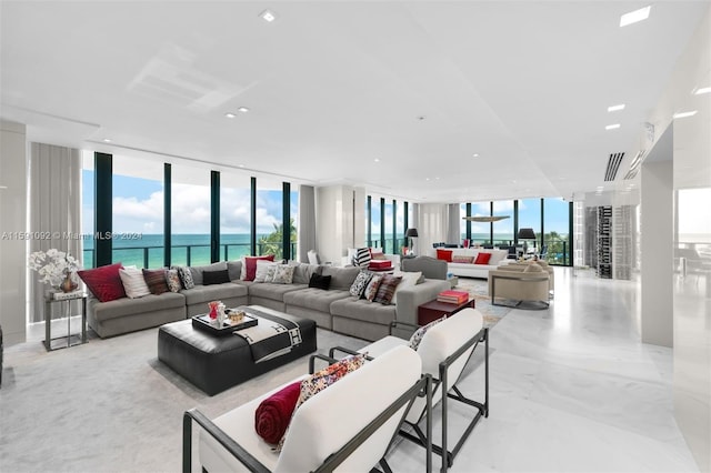 tiled living room featuring floor to ceiling windows, a water view, and a wealth of natural light