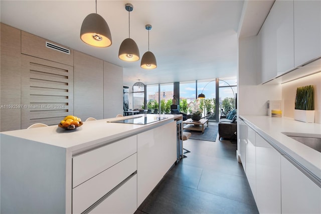 kitchen with dark tile floors, decorative light fixtures, white cabinets, and black electric cooktop