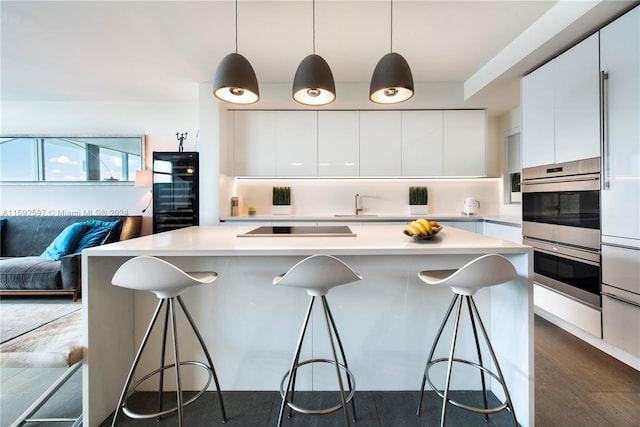 kitchen featuring white cabinets, stainless steel double oven, a center island, and a breakfast bar